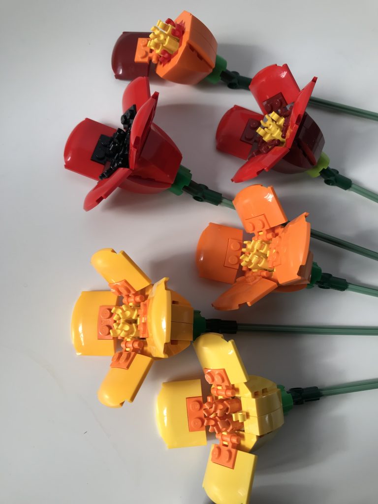 Orange poppy design by LEGO with alternate color variations: red, bright light orange, and yellow, lying on a white surface