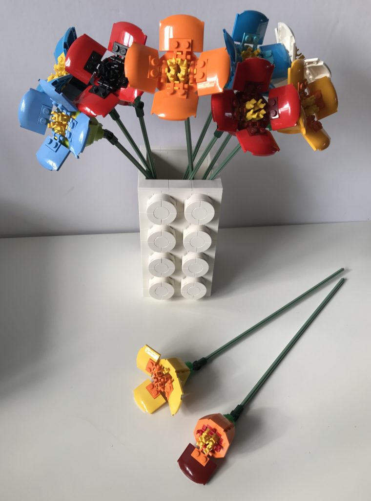 Poppy design by LEGO with alternate color variations: azure, white, medium blue, bright light orange, in a white large-format brick vase