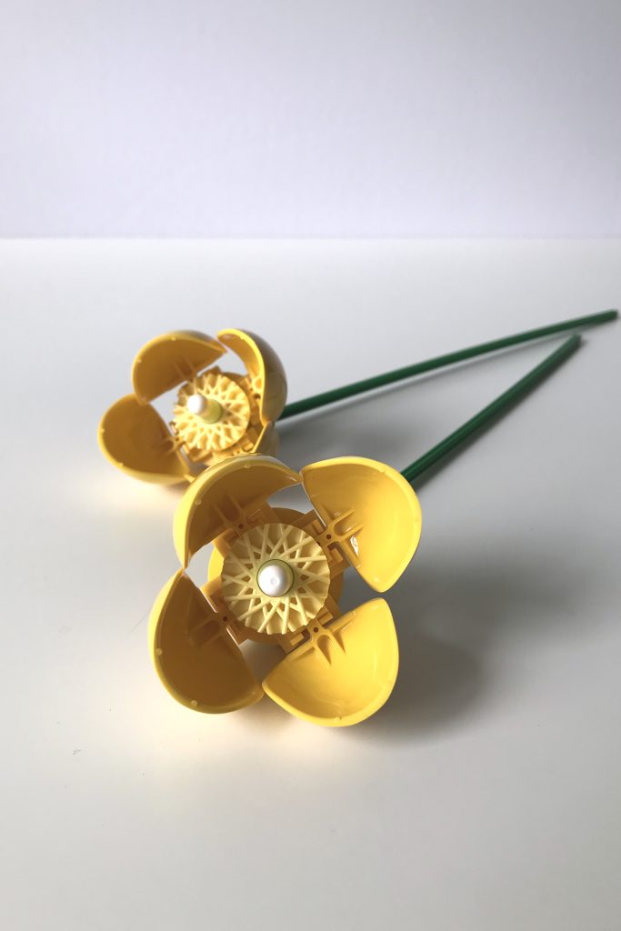 Yellow Welsh Poppy flowers from LEGO's Wildflower Bouquet set, lying on a white desk.