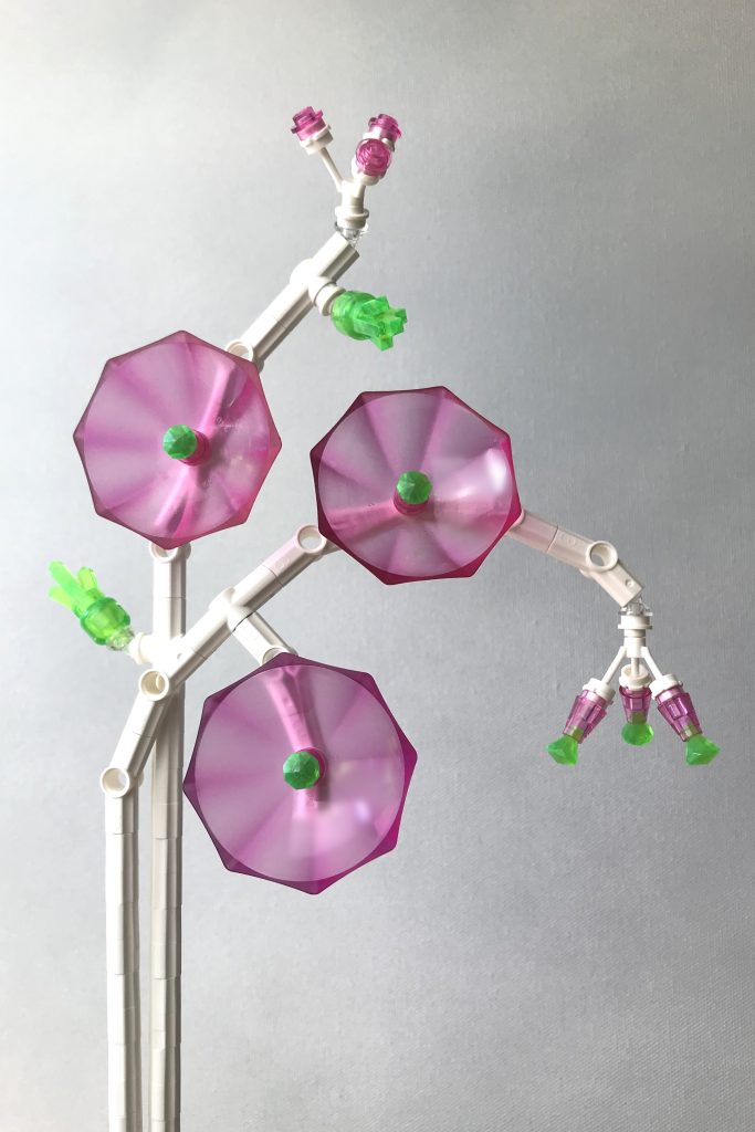 LEGO brick-built flowers MOC with white technic stems, transparent dark pink umbrellas as flowers, with transparent bright green gem centers, along with pink buds and green clusters of new leaves, on a light gray background.