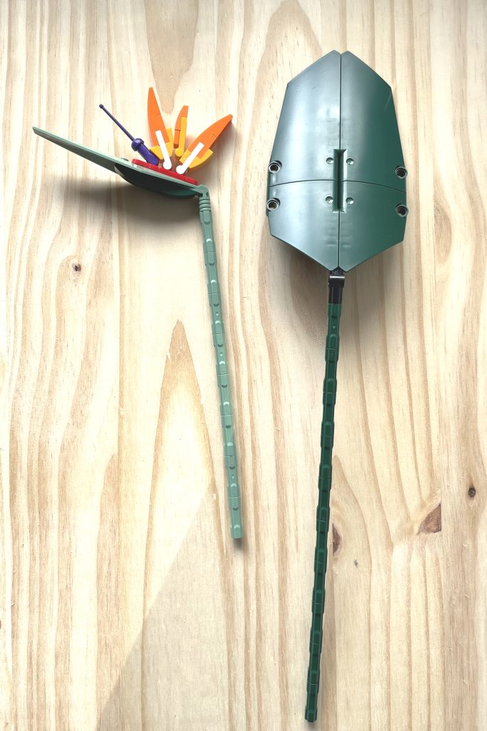 A LEGO flower and large leaf from the Bird of Paradise set lie on a light wood surface.